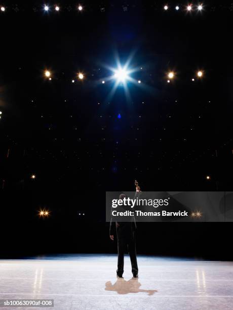 man holding up award towards audience, rear view - black awards stock-fotos und bilder