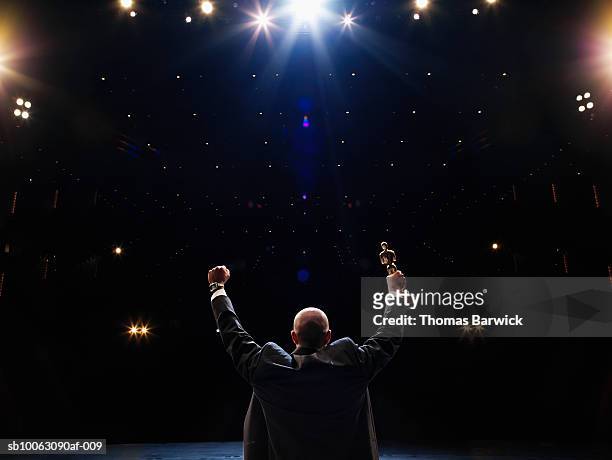 man holding up award towards audience, rear view - awards stock pictures, royalty-free photos & images