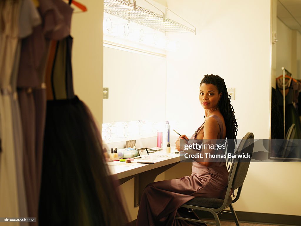 Female opera singer sitting in dressing room, smiling, portrait