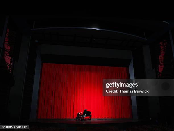 male pianist performing on grand piano on stage - pianist stock pictures, royalty-free photos & images