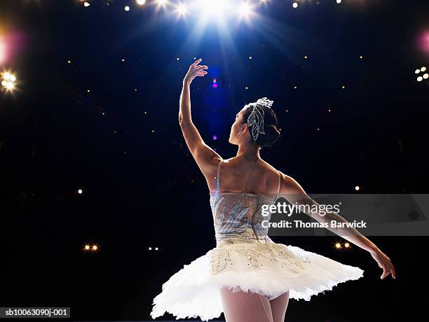 ballerina dancing on stage, arm raised, rear view - ballerina stockfoto's en -beelden