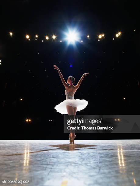 prima ballerina en pointe on stage, arms raised, rear view - bailarín fotografías e imágenes de stock