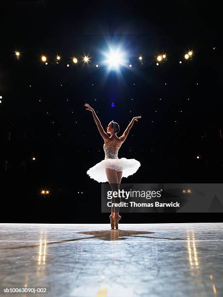 prima ballerina en pointe on stage, arms raised, rear view - ballet dancer stock pictures, royalty-free photos & images