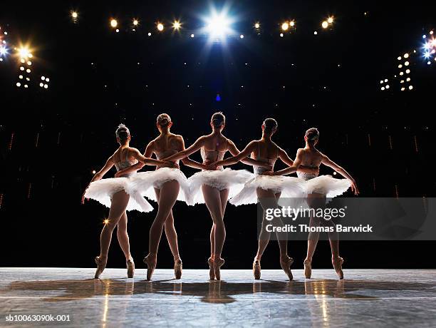 five ballerinas en pointe on stage, arms around each other, rear view - ballerina stock-fotos und bilder