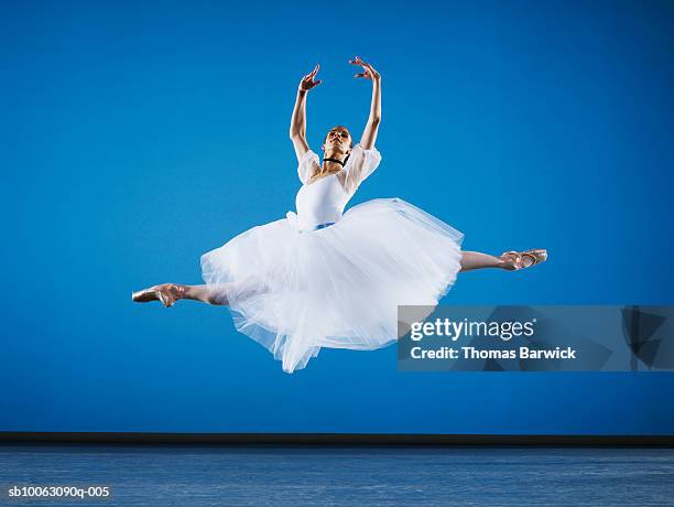 ballerina leaping on stage, arms raised - ballerinas stock-fotos und bilder