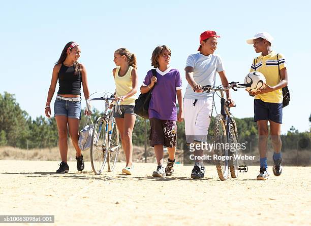 group of children and teenagers (11-14) walking on beach with bicycles and balls - solo bambini foto e immagini stock