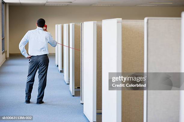 office worker standing besides cubicles using landline phone, rear view - landline phone imagens e fotografias de stock
