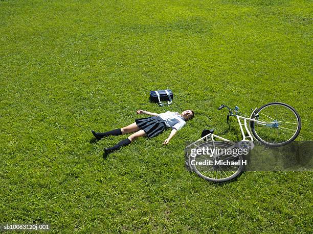 teenage schoolgirl (16-17) lying on lawn beside bicycle, elevated view - position physique photos et images de collection