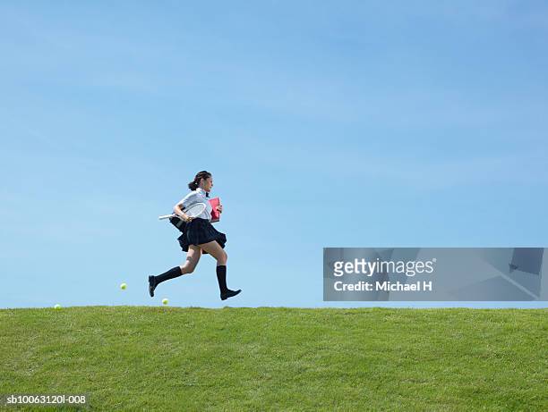 teenage schoolgirl (16-17) running and dropping tennis balls, side view - female high school student stock pictures, royalty-free photos & images