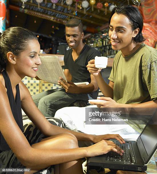 young couple in caft, man drinking coffee, woman using laptop - caft stock pictures, royalty-free photos & images
