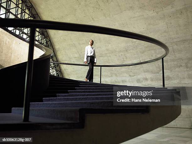 business woman walking down stairs in office, low angle view - arquitectura fotografías e imágenes de stock