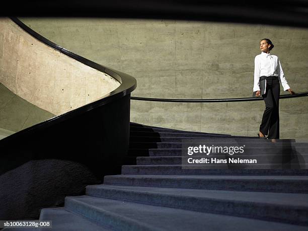 business woman walking down stairs in office, low angle view - architecture low angle stock-fotos und bilder