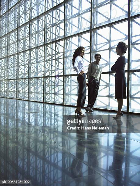 three business people talking by window - architectonisch element stockfoto's en -beelden