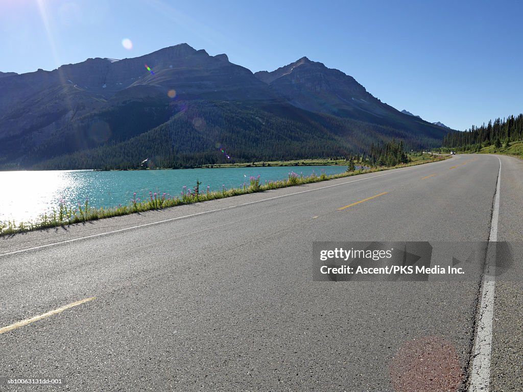 Canada, Alberta, Banff National Park, empty highway by lake, lens flare