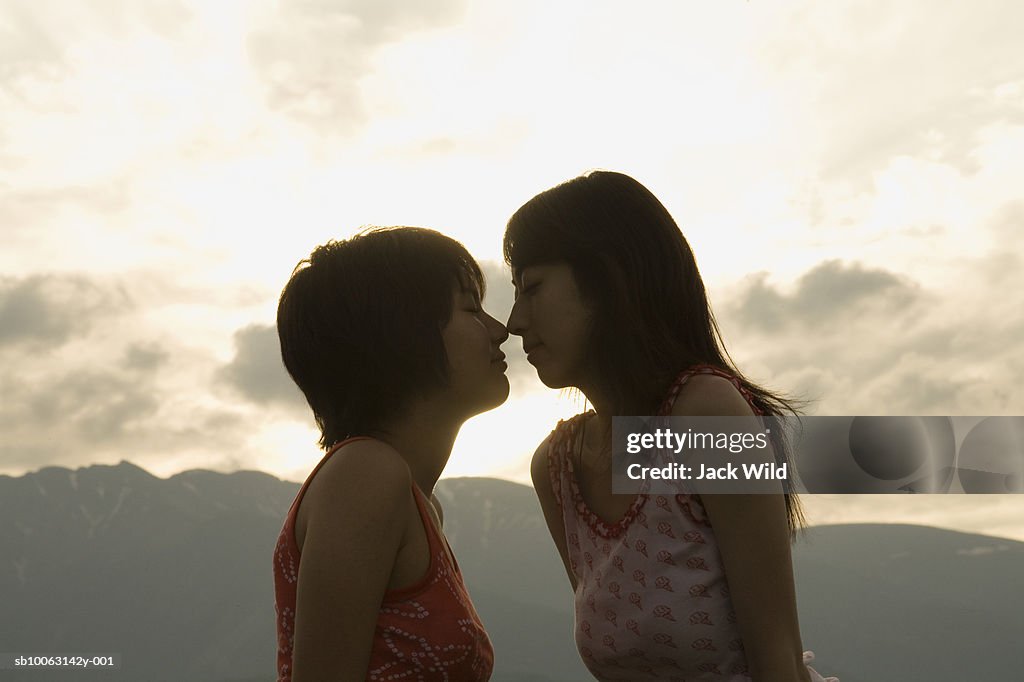 Young woman and teenage girl (14-15) rubbing noses, low angle view