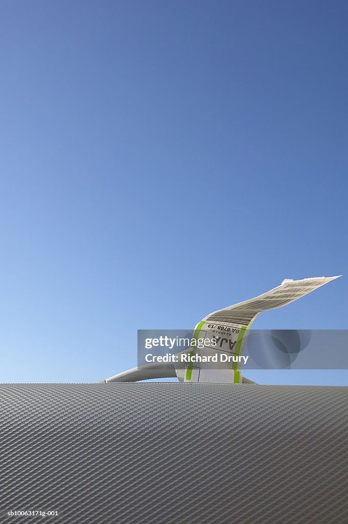 Airline label attached to suitcase handle, close-up, against blue sky