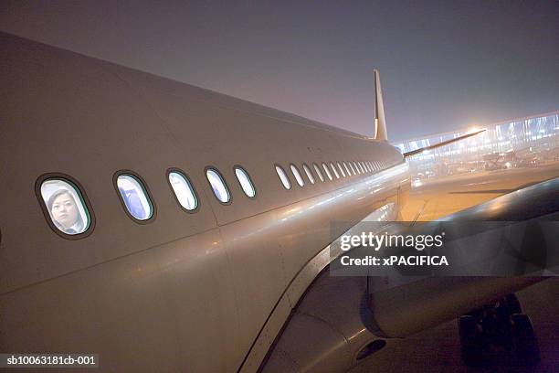 close-up of airplane at airport with faces at windows, night - airplane window exterior stock-fotos und bilder