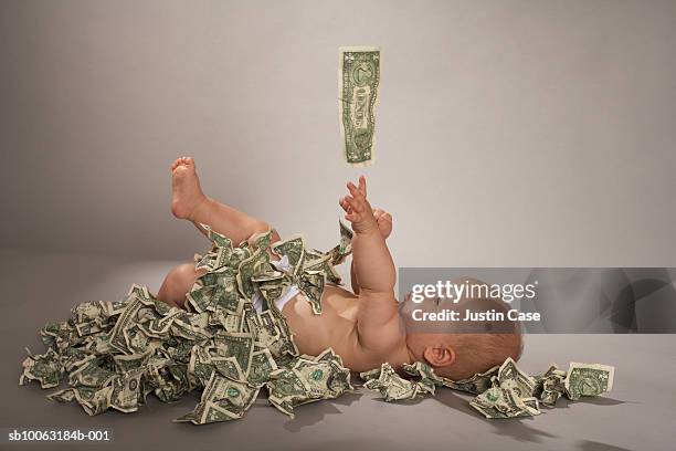baby girl (5 months) lying down covered with us dollar bills falling from above - silver spoon in mouth stock pictures, royalty-free photos & images