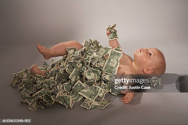 baby girl (5 months) lying down covered with us dollar bills - girl lying down stock pictures, royalty-free photos & images