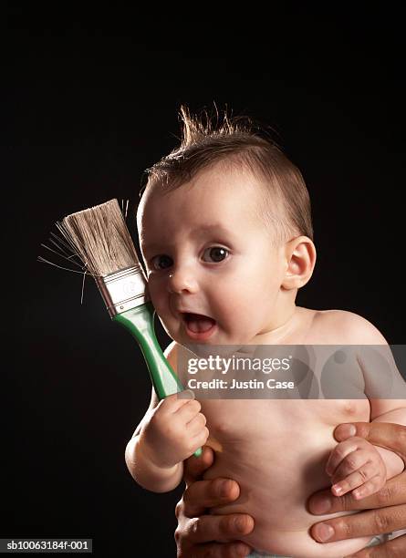 man holding baby boy (5 months) with paintbrush, portrait - baby creativity ideas stock-fotos und bilder