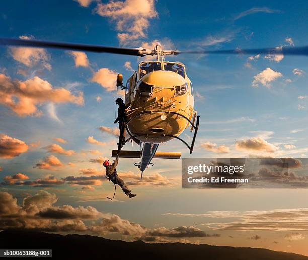 man being pulled by rescue helicopter - rescue worker stock-fotos und bilder