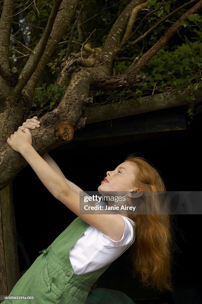 Girl (8-9) holding tree branch outdoors