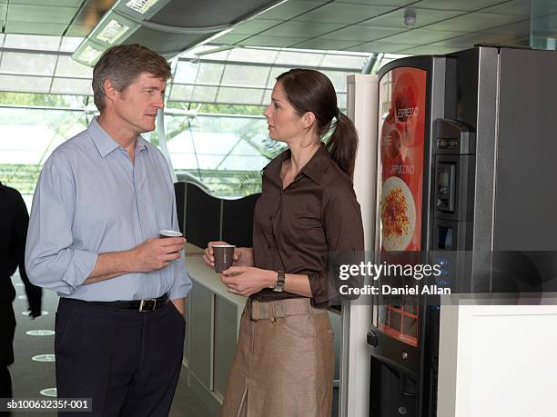 office colleagues standing next to coffee machine in office, talking - vending machine stock-fotos und bilder