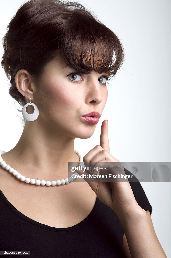 Young woman making silence gesture, portrait