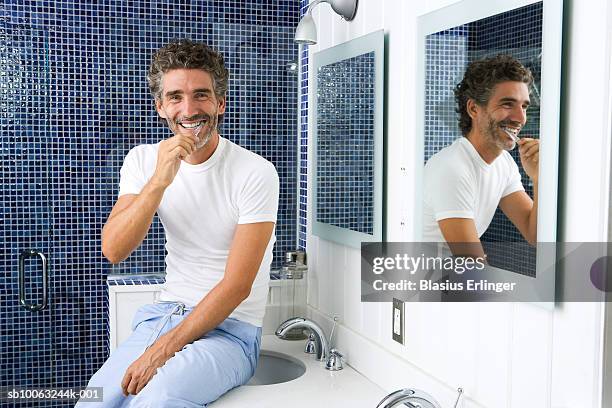 man brushing teeth in bathroom - toothbrush ストックフォトと画像