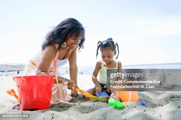 mother and daughter (2-3) playing on beach - african girls on beach stockfoto's en -beelden