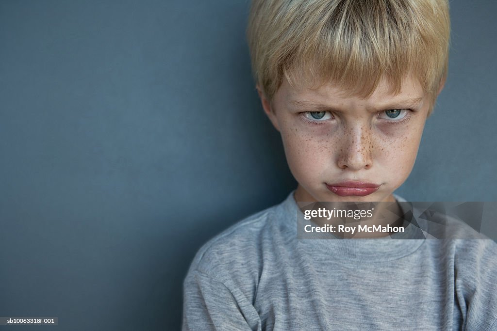 Boy (8-9 years) making face, studio shot, portrait