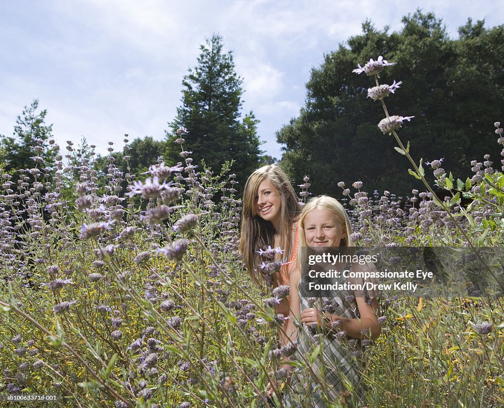 Two girls (8-11 years) standing in field of flowers, portrait