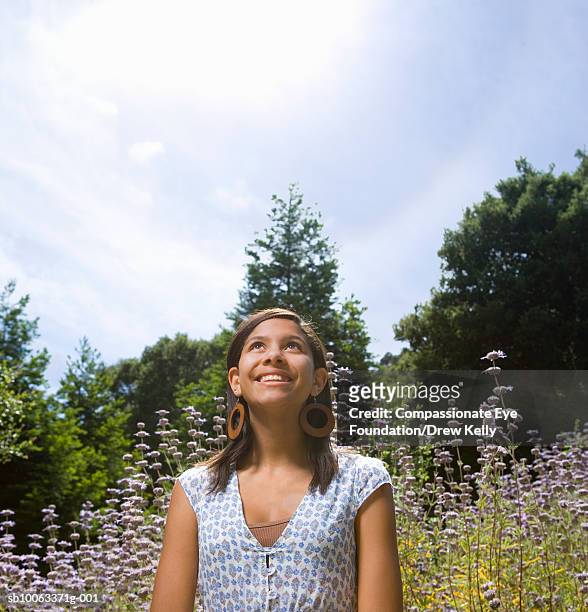 teenage girl (13-14 years) standing on flower field, looking up - 13 15 years stock-fotos und bilder