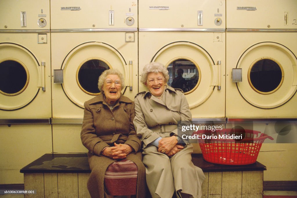 Two senior woman in launderettes, laughing, portrait