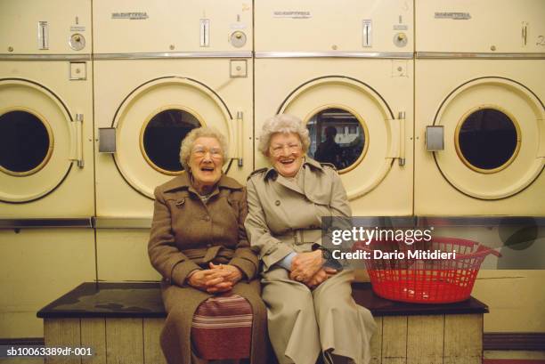 Two senior woman in launderettes, laughing, portrait