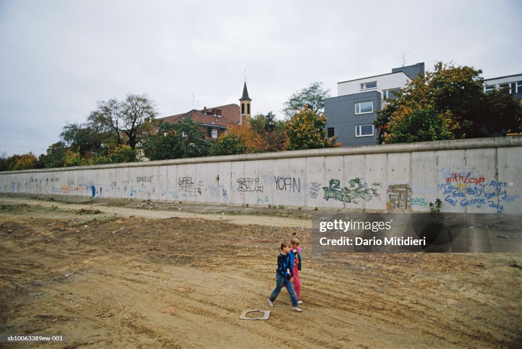 Berlin, Germany, children (6-7) walking down Bernauer Strasse with preserved part of Berlin Wall