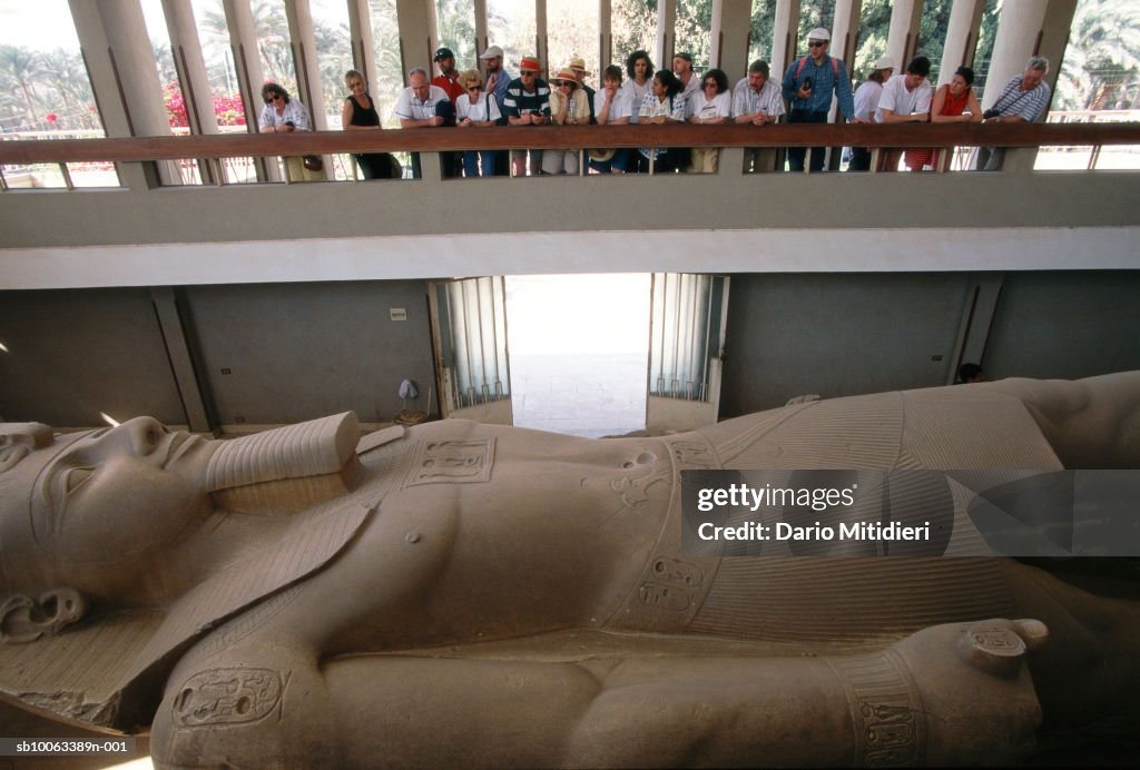 Group of tourists looking at huge sculpture of pharaoh