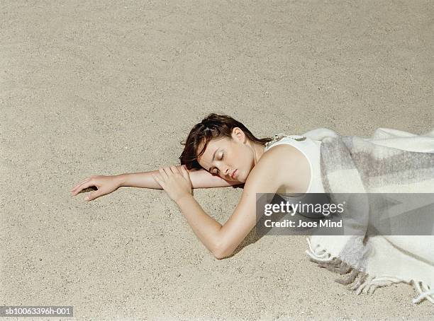 young woman lying on beach, eyes closed, elevated view - allongé sur le devant photos et images de collection