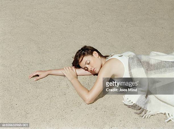 young woman lying on beach, eyes closed, elevated view - china foto e immagini stock