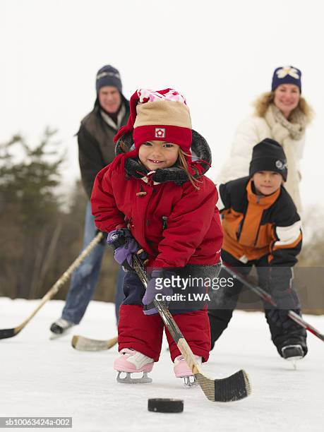 family playing ice hockey on frozen lake, smiling - canada hockey stock-fotos und bilder