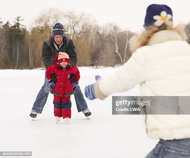 parents teaching daughter (3-5) to skate on frozen lake - learning to ice skate stock pictures, royalty-free photos & images