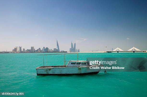 fishing boat in sea, manama skyline in background - bahrein stock-fotos und bilder