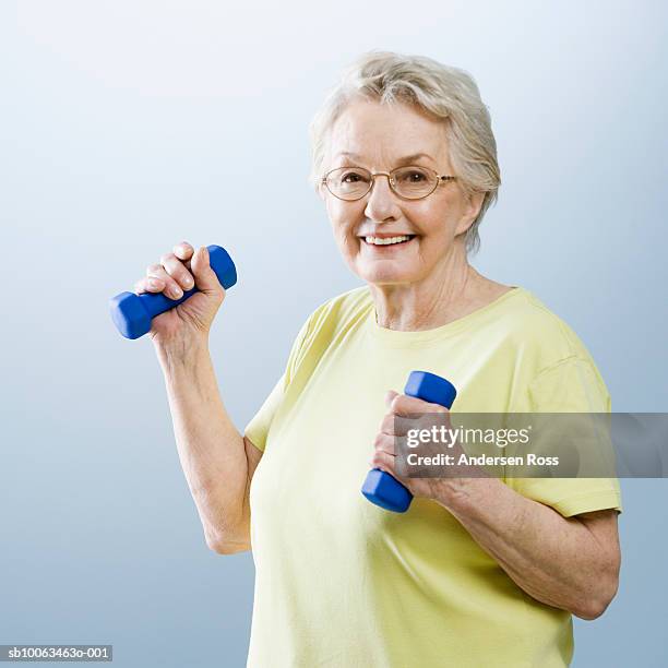 senior woman lifting small weights, portrait - weight lifting stock-fotos und bilder