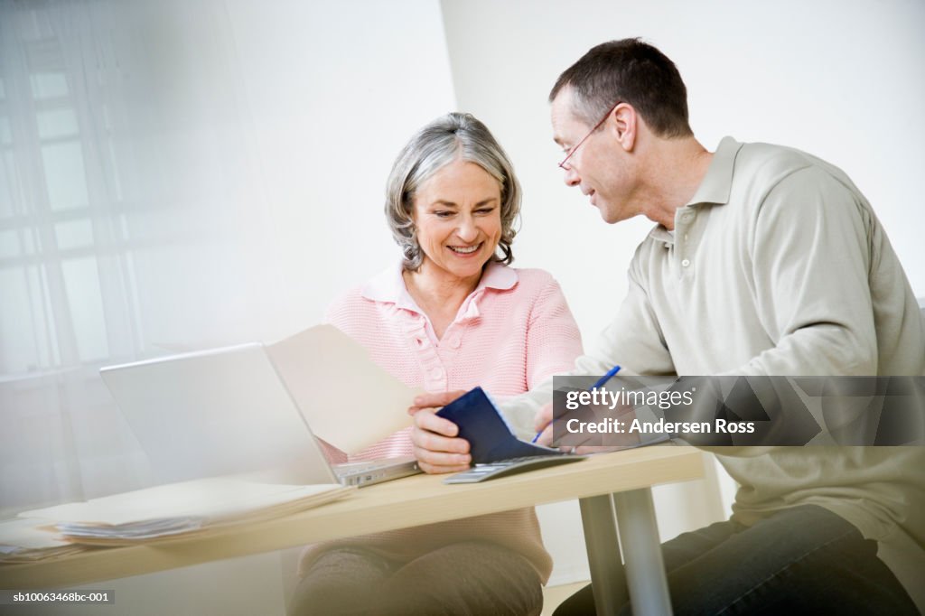 Mature couple doing paperwork using laptop
