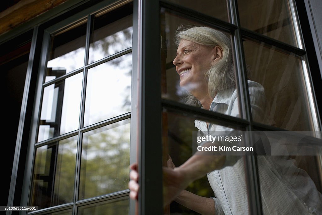 Mature woman in window, smiling, low angle view