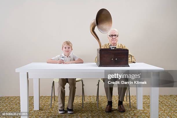 boy (10-11) with mp3 player and man with gramophone sitting at table - boy ipod stock pictures, royalty-free photos & images