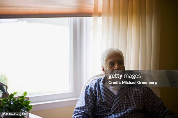 senior man in bathrobe sitting in armchair by window, portrait - michael sit stock pictures, royalty-free photos & images