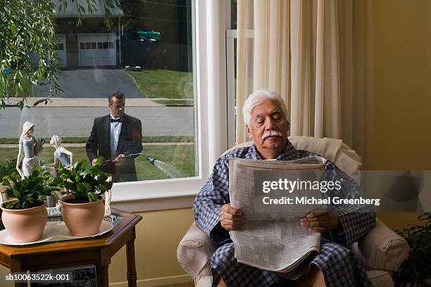 senior man in armchair, reading newspaper, butler watering garden outside window - newspaper luxury stock-fotos und bilder