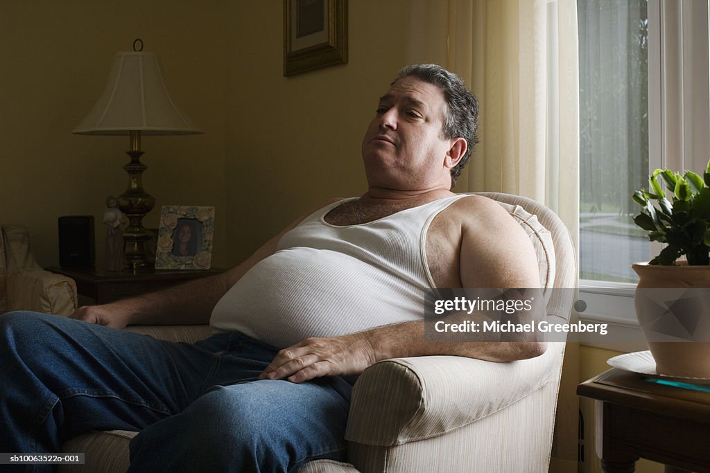 Mature overweight man sitting in armchair
