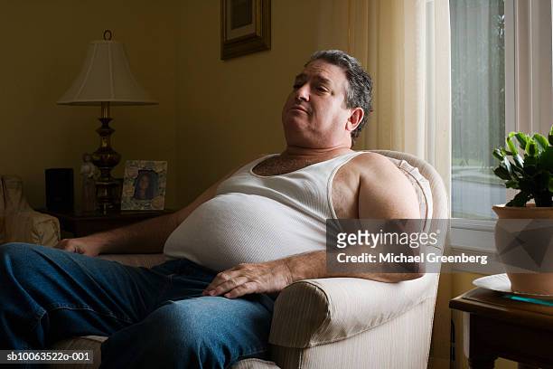 mature overweight man sitting in armchair - overweight bildbanksfoton och bilder